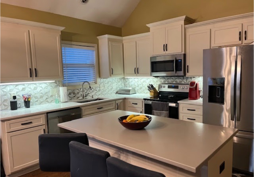 Premium modern farmhouse kitchen styled with warm off-white shaker cabinets, mosaic geometric backsplash, and quartz island